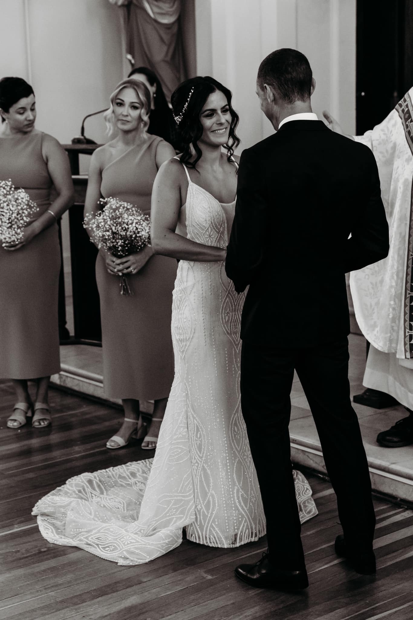 Bride and groom standing together during their wedding ceremony in a black and white photo.